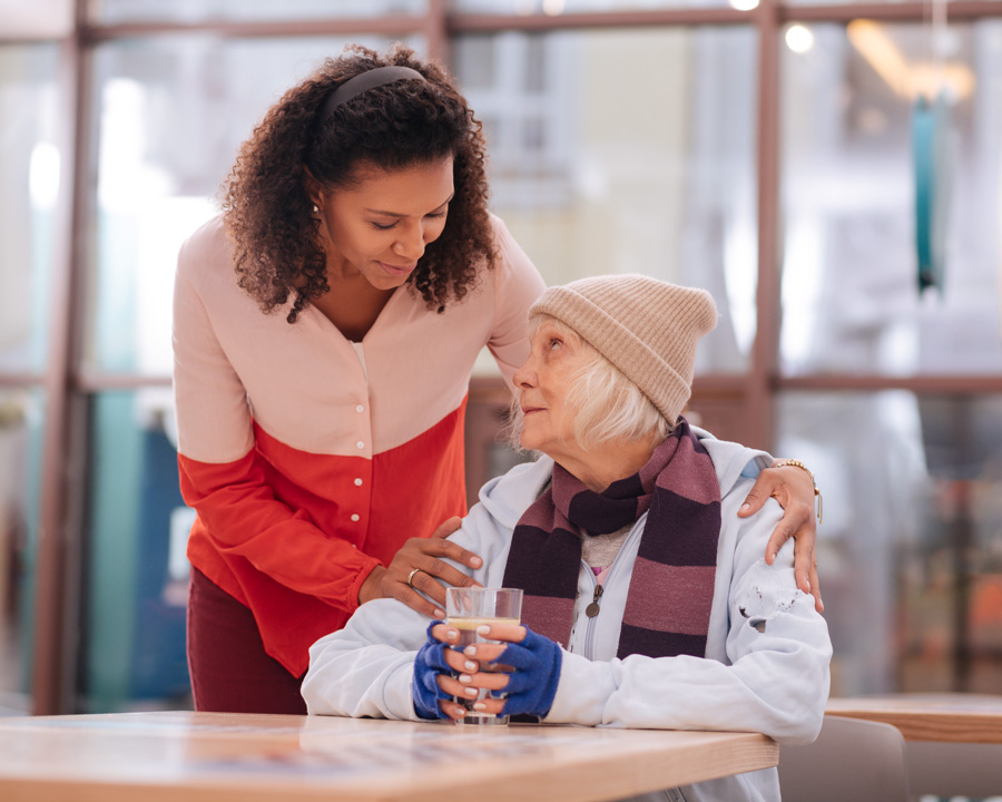 caring woman with hand on elderly homeless womans shoulder